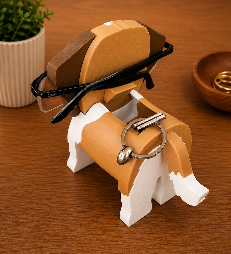 May include: A wooden dog-shaped desk organizer in brown, white, and black. The organizer holds a pair of black-framed glasses and a silver keychain. The dog has a playful design, perfect for holding small items on a desk or nightstand.