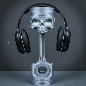 May include: A silver-colored, skull-shaped piston with a set of black headphones resting on top. The piston is a unique decorative item, possibly a headphone stand, with a detailed skull design and a mechanical aesthetic.