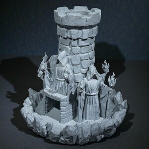 K&ouml;nnte beinhalten: Ein grauer, 3D-gedruckter Fantasy-Burgturm mit zwei Figuren in Roben, die Fackeln halten. Der Turm hat eine zinnenbewehrte Spitze und ist von einem felsigen Sockel umgeben. Die Figuren sind detailliert mit Kapuzenm&auml;nteln und St&auml;ben.