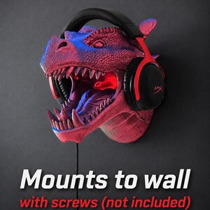 May include: A red and blue dragon head wall mount with a pair of black and red headphones. The dragon's mouth is open, revealing sharp teeth and a red interior. The text "Mounts to wall with screws (not included)" is displayed.