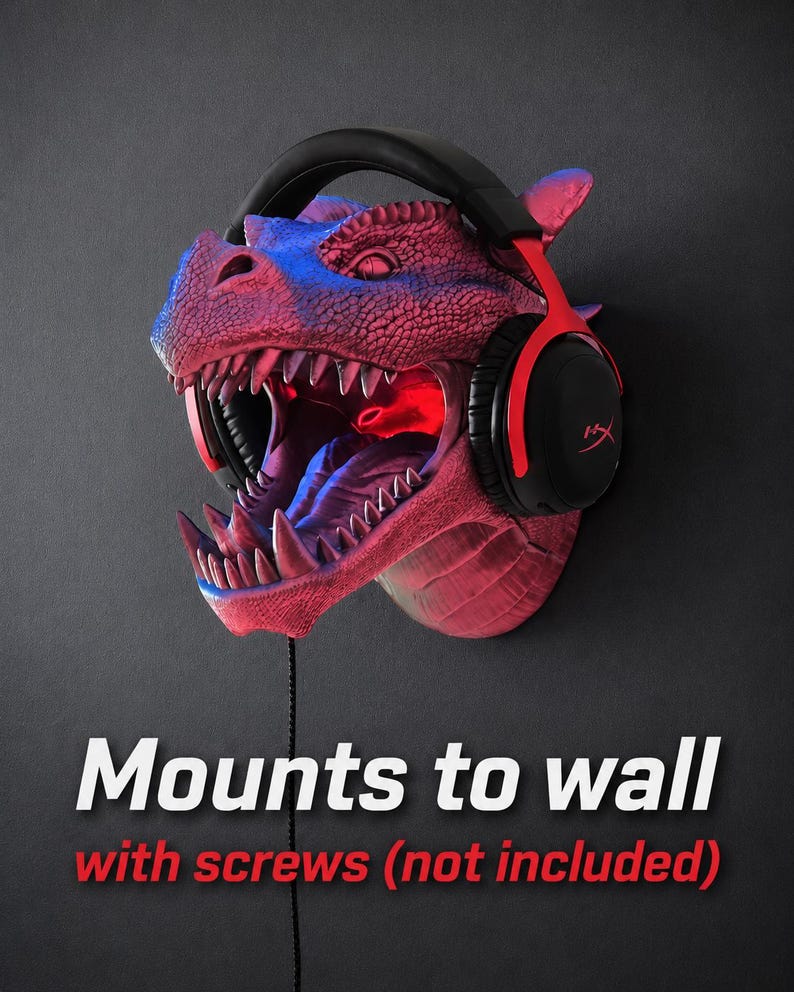 May include: A red and blue dragon head wall mount with a pair of black and red headphones. The dragon's mouth is open, revealing sharp teeth and a red interior. The text "Mounts to wall with screws (not included)" is displayed.