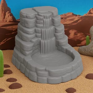 Puede incluir: Una escultura de cascada gris escalonada con una cuenca. La cascada tiene m&uacute;ltiples niveles, que se asemejan a rocas apiladas. El fondo presenta un paisaje des&eacute;rtico con cielo azul y cactus.