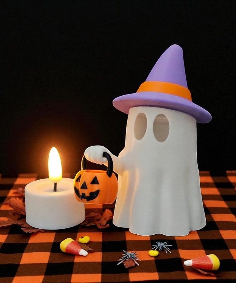 May include: A white ghost figure wearing a purple and orange witch hat, holding an orange jack-o'-lantern bucket. A lit white candle and Halloween candies are on a black and orange checkered surface. Halloween-themed decor.