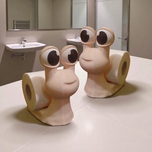 May include: Two whimsical snail-shaped toilet paper holders. The holders are a light beige color with large, cartoonish eyes and a smiling face. Each snail holds a roll of white toilet paper, adding a fun touch to bathroom decor.
