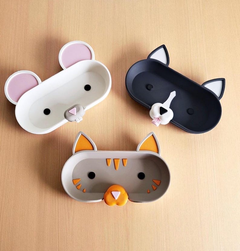 Pode incluir: Tr&ecirc;s bandejas em forma de animais: um rato branco com orelhas cor-de-rosa, um gato preto com orelhas brancas e um gato cinzento com orelhas laranja. Cada bandeja tem formato oval, ideal para guardar pequenos objetos.