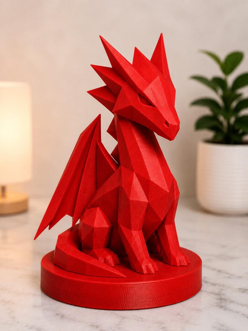 May include: A red, geometric dragon sculpture with sharp angles and a detailed design. The dragon has wings and is seated on a round base. The sculpture is a decorative item.