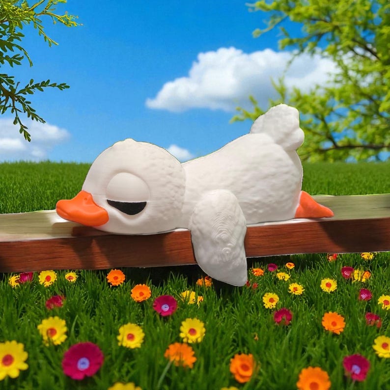 May include: A white, cartoon-style duck with an orange beak and feet is resting on a wooden bench. The duck is lying down with its eyes closed. The scene is set outdoors with a blue sky, clouds, and a vibrant flower garden.