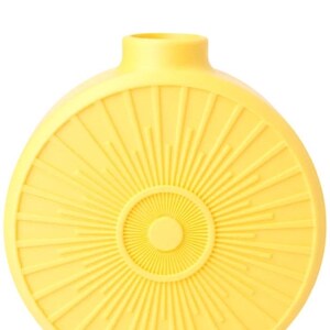 May include: A yellow ceramic vase with a sunburst design. The vase has a round body with a narrow neck and a circular pattern radiating from the center. The color is a bright, sunny yellow.