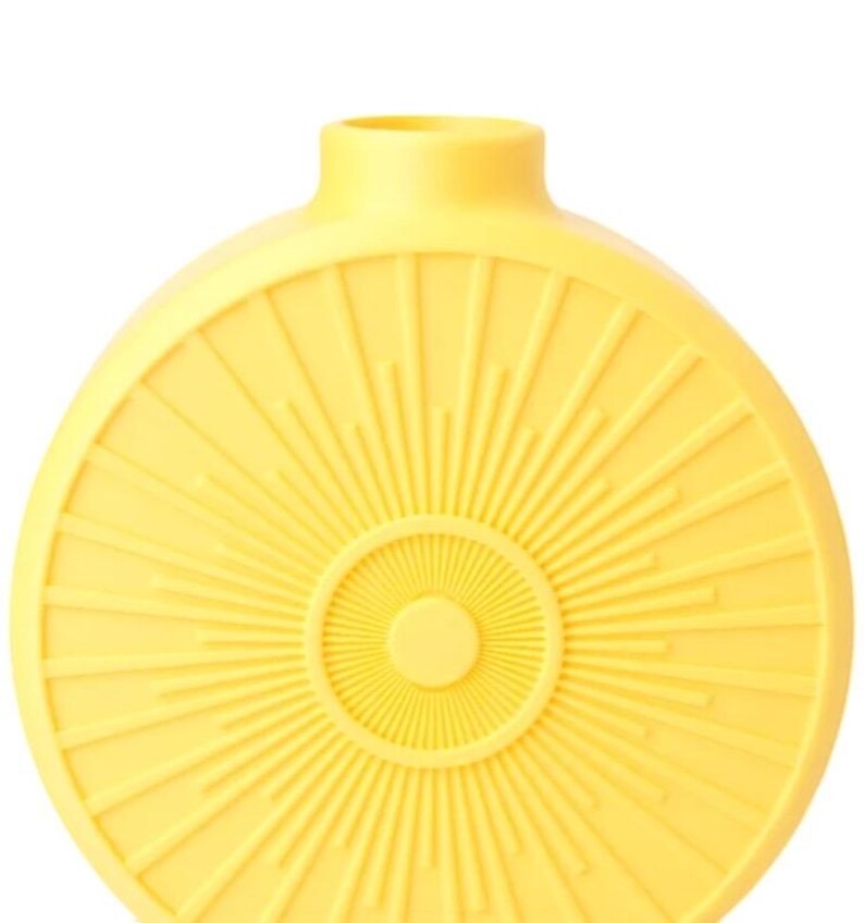 May include: A yellow ceramic vase with a sunburst design. The vase has a round body with a narrow neck and a circular pattern radiating from the center. The color is a bright, sunny yellow.