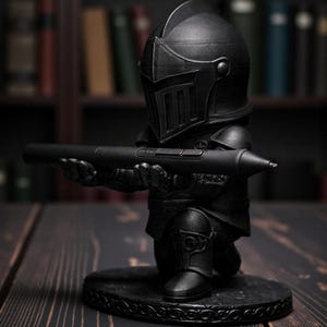 May include: A black knight figurine holding a black pen. The knight is kneeling on a round base with an ornate design. The background includes a bookshelf with books.