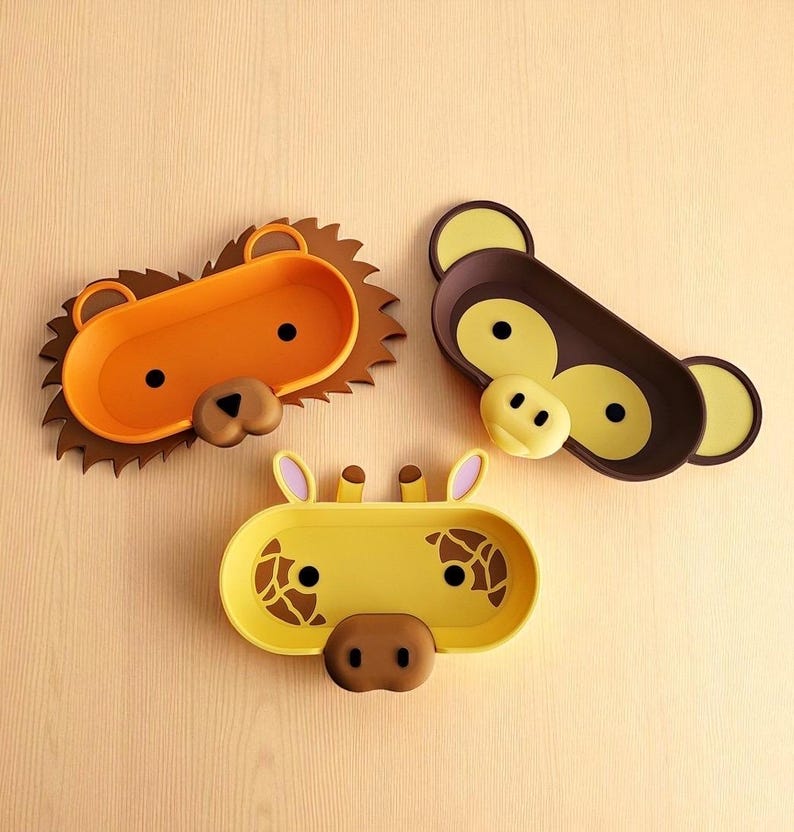 Puede incluir: Tres bandejas con forma de animales: un le&oacute;n, un mono y una jirafa. El le&oacute;n es naranja con una melena marr&oacute;n, el mono es marr&oacute;n con detalles amarillos y la jirafa es amarilla con manchas marrones. Cada bandeja tiene un dise&ntilde;o de cara.