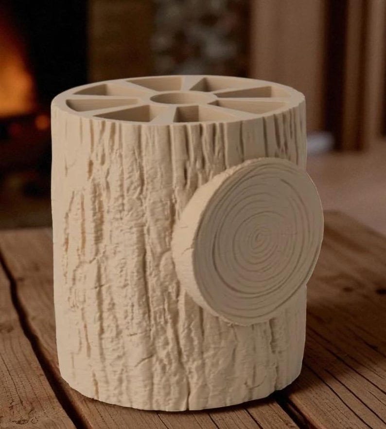 May include: A beige, cylindrical pen holder designed to resemble a tree trunk. The top features multiple compartments, and a circular, cross-section design is attached to the side. The holder sits on a wooden surface.