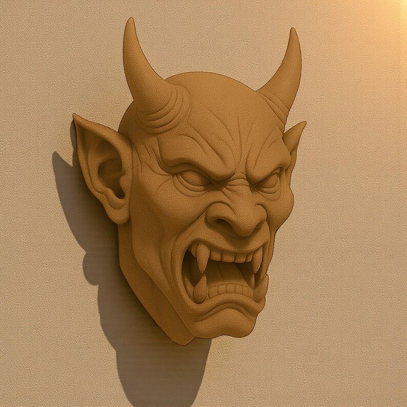 May include: A detailed, tan-colored wall sculpture of a demonic face with horns, pointed ears, and an open mouth revealing sharp teeth. The sculpture is mounted on a light beige wall, casting a shadow.