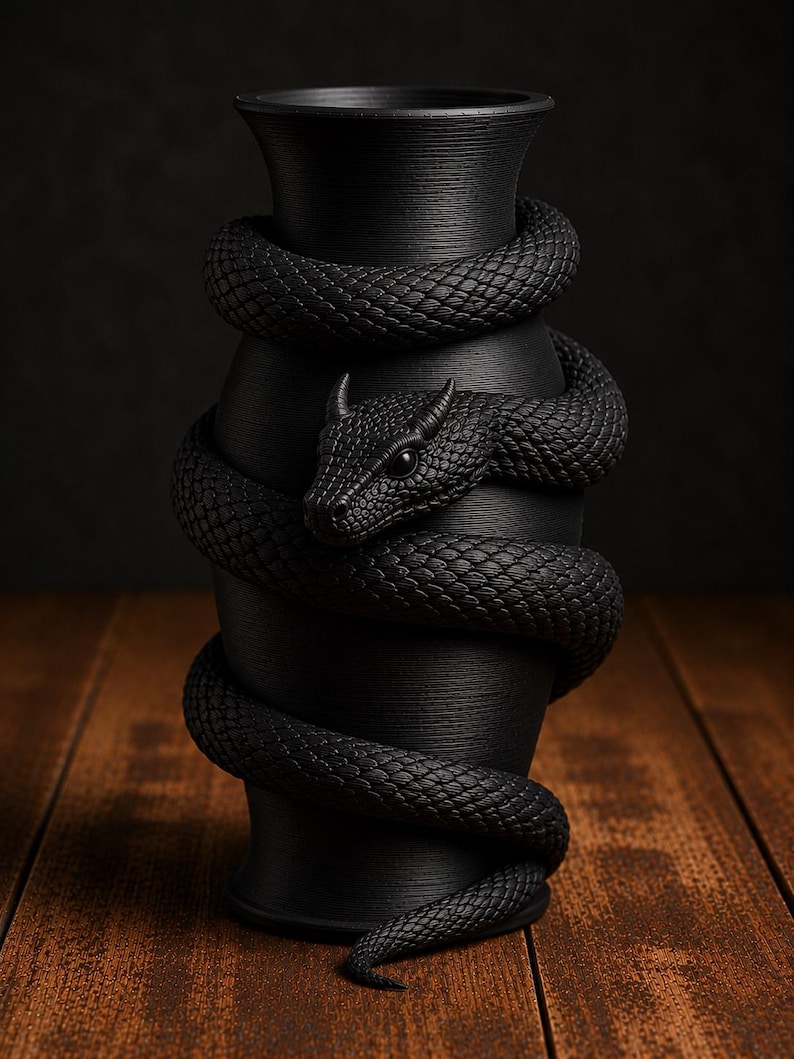 May include: A black vase with a textured surface, wrapped by a detailed, coiled snake. The snake's head is visible, with intricate scales and a menacing gaze. The vase sits on a wooden surface.