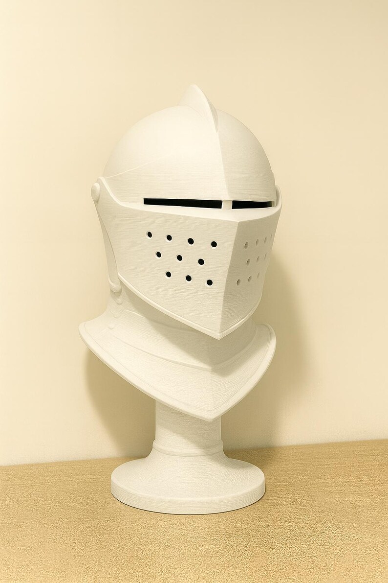 May include: A white knight's helmet sculpture with a visor featuring small circular holes. The helmet is mounted on a white pedestal, creating a bust-like appearance. The sculpture is made of a textured material.