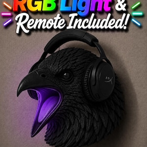 May include: A black raven head sculpture with an open beak, lit with purple light. The raven wears black headphones. The text "RGB Light & Remote Included!" is displayed above the raven's head.