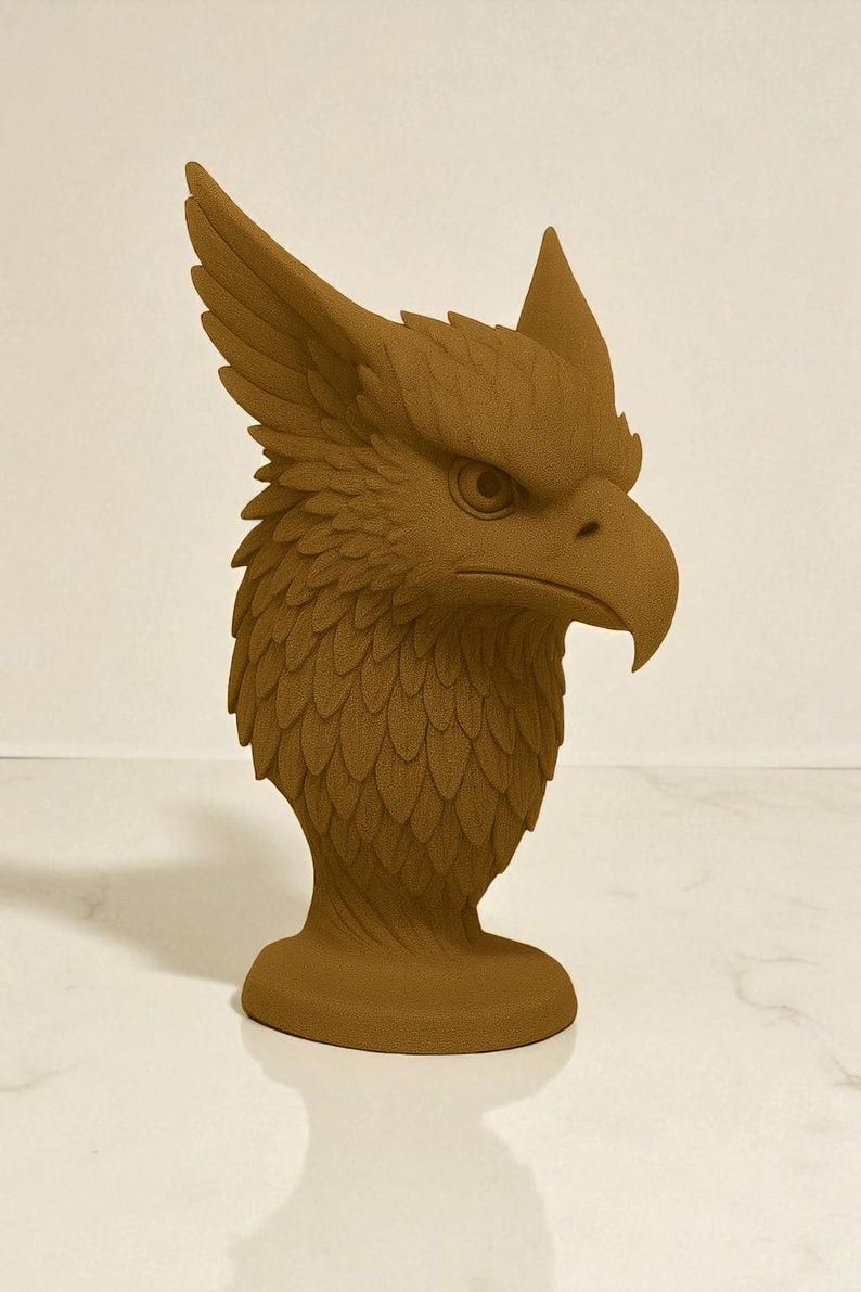 May include: A brown griffin head sculpture. The sculpture features detailed feather and scale textures, with a prominent beak and piercing eye. The griffin has large, upright ears and a detailed mane. The sculpture is mounted on a round base.