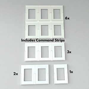 Pu&ograve; includere: Set di cornici per foto in plastica bianca in varie quantit&agrave;, tra cui set da 6, 3, 2 e 1. Il testo "Includes Command Strips" &egrave; stampato sull'immagine. Le cornici hanno un design rettangolare.