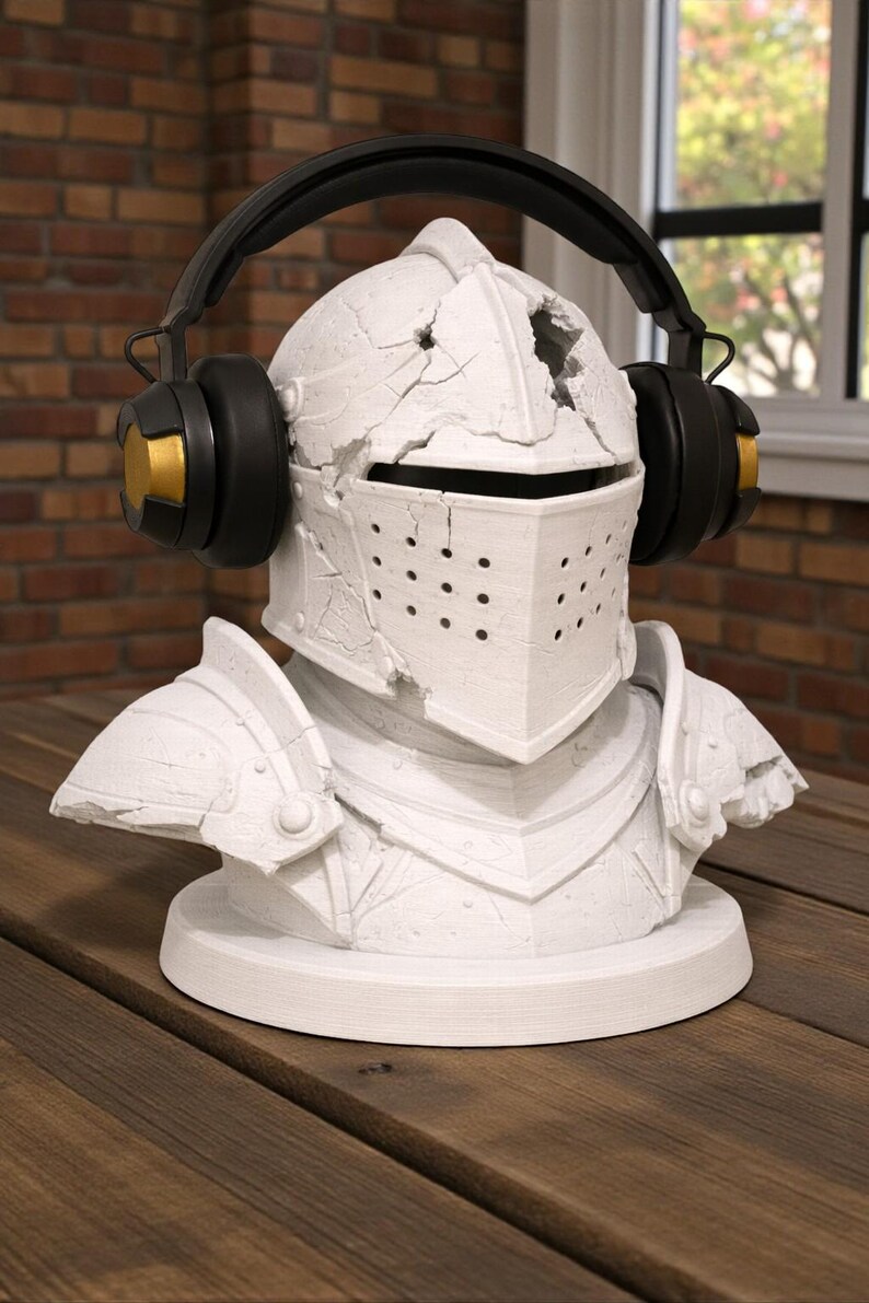 Puede incluir: Busto de casco de caballero blanco con auriculares negros y dorados. El casco tiene un aspecto desgastado y agrietado. Los auriculares son negros con detalles dorados en los auriculares. El busto est&aacute; sobre una base redonda.