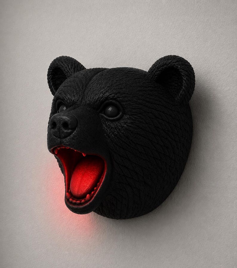 May include: A black bear head wall decor with an open mouth revealing a red interior. The bear has textured fur and is mounted on a light gray wall. The bear's mouth is open, and the interior is illuminated with a red light.