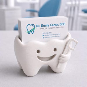 May include: A white, tooth-shaped business card holder with a smiling face and a floss pick. The holder contains a stack of white business cards with the text "Dr. Emily Carter, DDS" and contact information. The design is clean and modern.