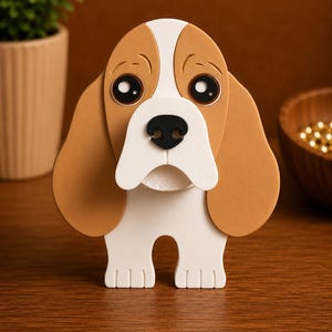 May include: A decorative dog figurine with a brown and white color scheme. The dog has large, expressive eyes, floppy ears, and a black nose. The figurine is made of layered materials and stands upright on a wooden surface.