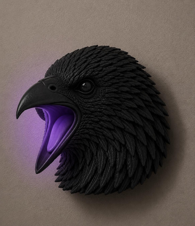 May include: A black raven head sculpture with an open beak, revealing a purple interior. The sculpture is mounted on a neutral-toned wall. The raven's feathers are detailed, and the eye is visible.
