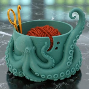 May include: A teal octopus-shaped yarn bowl with a ball of orange yarn inside. Gold crochet hooks and scissors are placed in the bowl. The bowl has a tentacle that curves upward, and the octopus's head is on the side.