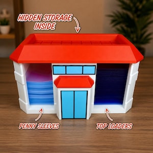 May include: A white and red storage container shaped like a building, with blue accents. The container has the text "HIDDEN STORAGE INSIDE", "PENNY SLEEVES", and "TOP LOADERS". The roof is red, and the doors and windows are blue.