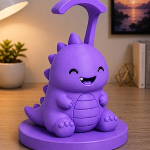 May include: A purple dinosaur-shaped desk lamp with a curved top and a smiling face. The lamp has a round base and a textured surface. The lamp is sitting on a wooden surface.