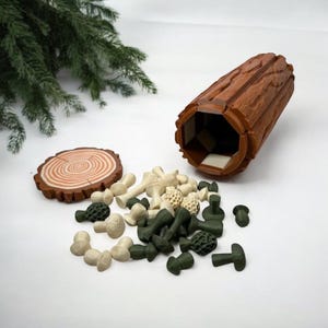 May include: A brown, hollow log-shaped container with a textured exterior, alongside a wooden slice and a collection of small, mushroom-shaped toys in shades of green and beige. The toys are scattered around the log.