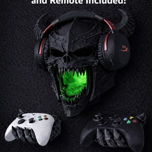 May include: A black skull-shaped wall mount with a green glowing mouth, holding a pair of black and red gaming headphones. Two game controllers, one white and one black, are positioned below. The text "RGB Puck Light and Remote Included!" is displayed above.