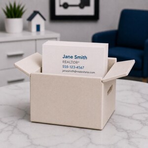May include: A beige business card holder with a stack of white business cards. The cards display the name "Jane Smith, REALTOR&reg;", a phone number, and an email address. The holder is on a marble-patterned table.