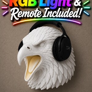 May include: A white eagle head sculpture with a black headset. The eagle's beak is open, revealing a light yellow interior. The text "RGB Light & Remote Included!" is displayed above the sculpture in colorful letters.