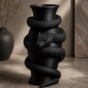 May include: A black ceramic vase with a textured surface, featuring a detailed, coiled snake design wrapped around the body. The snake's head is visible, adding a striking focal point. The vase has a wide mouth and a flared base, suitable for home decor.
