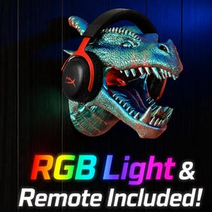 May include: A dragon head wall mount with a headset. The dragon is painted in shades of blue and green with red accents inside the mouth. The headset is black and red. The text "RGB Light & Remote Included!" is displayed in rainbow colors.