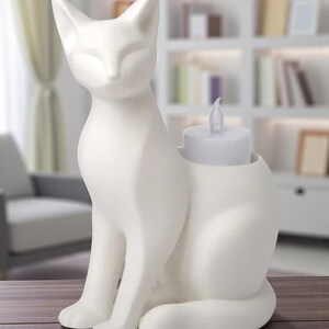 Op de afbeelding: Een witte keramische kattenfiguur met een kaarsenhouder. De kat zit rechtop met gesloten ogen. Een witte LED-kaars zit in de houder. De figuur staat op een houten oppervlak.