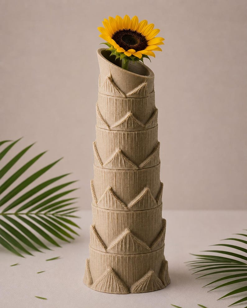 May include: A tall, beige vase with a textured, stacked design, holding a vibrant yellow sunflower. The vase has a unique, angled opening. The sunflower's dark center contrasts with its bright yellow petals.