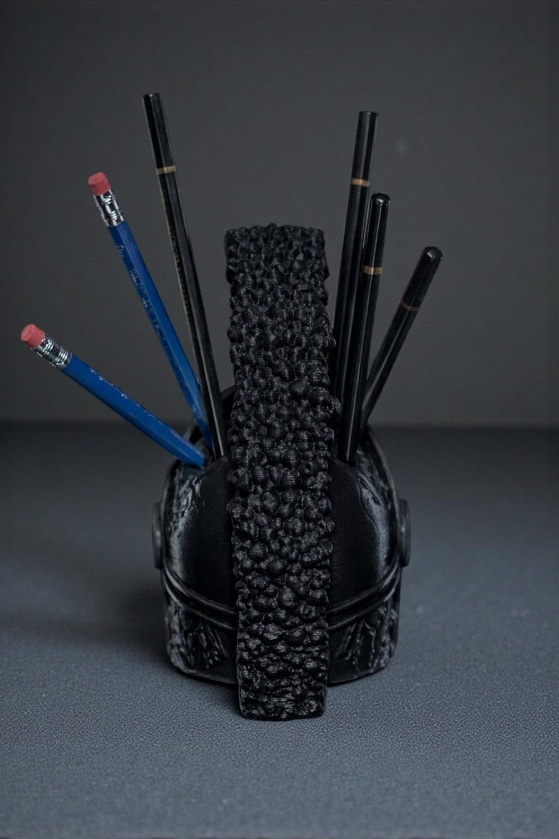 Puede incluir: Organizador de escritorio negro con una parte delantera decorativa texturizada y un divisor central texturizado. Los l&aacute;pices de varios colores se colocan dentro del organizador, incluidos l&aacute;pices azules con gomas rosas y l&aacute;pices negros.