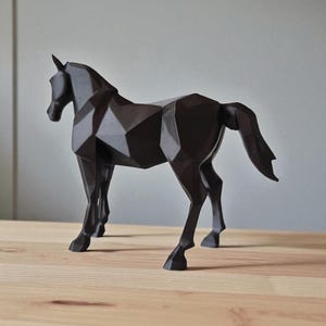 以下が含まれることがあります： 濃い茶色の幾何学的な馬の彫刻。馬は木製の表面に立っています。彫刻は多面的なデザインで、モダンで芸術的な外観を与えています。馬の形は、頭、体、脚がはっきりと定義されています。