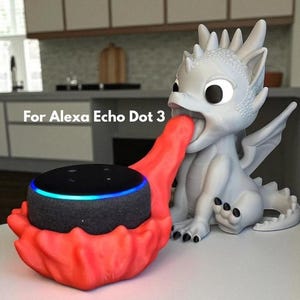 May include: A white dragon-shaped speaker holder with a red accent holding a black Alexa Echo Dot 3. The dragon has large eyes and a detailed design. The text "For Alexa Echo Dot 3" is visible.