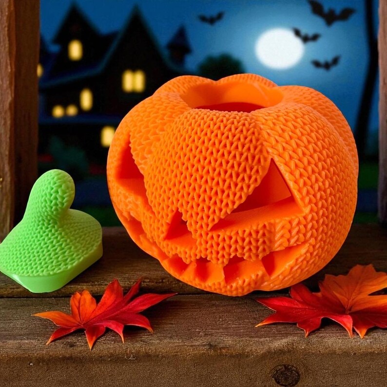 May include: An orange, textured pumpkin with carved-out eyes, nose, and mouth, sits next to a green object and red and orange leaves. The background features a spooky house, a full moon, and bats, creating a Halloween theme.