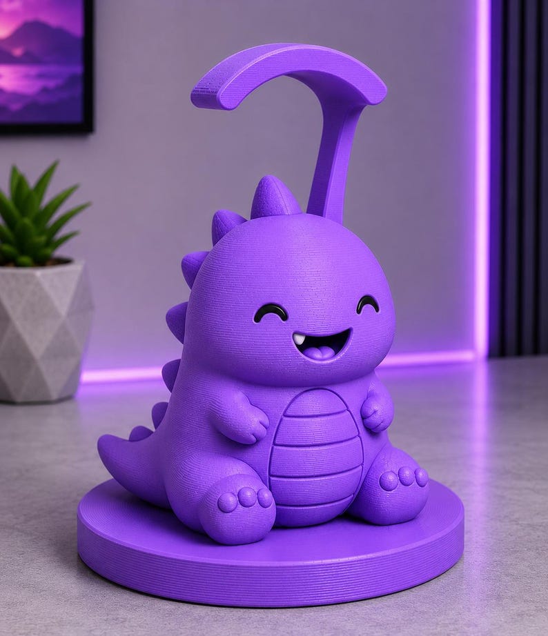 May include: A purple dinosaur-shaped desk lamp with a smiling face and a curved handle. The lamp sits on a round base and has a textured surface. The background includes a small potted plant and a purple-lit wall.