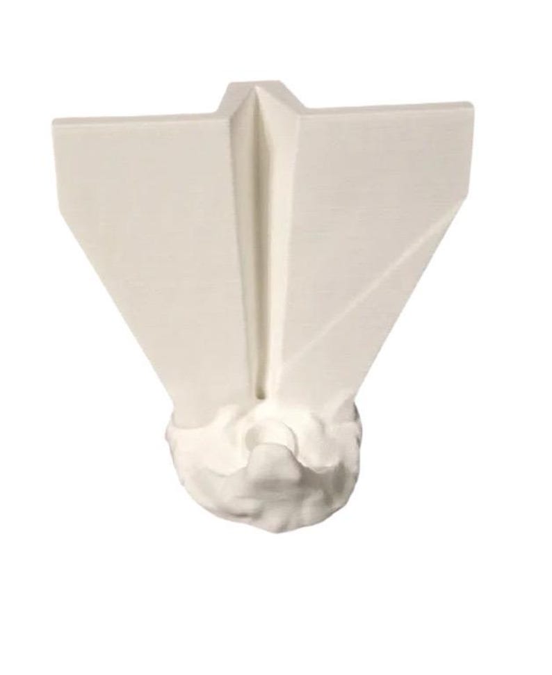 May include: A white, abstract sculpture with a geometric design. The sculpture has a V-shaped top with angled sides and a textured, cloud-like base. The piece is made of a solid, opaque material.
