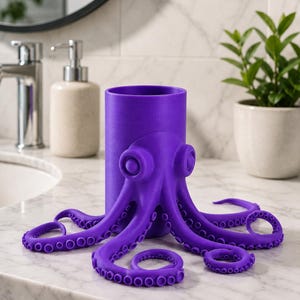 May include: A vibrant purple octopus-shaped toothbrush holder. The holder features a cylindrical body with an octopus design, including tentacles and eye details. The holder is made of a solid, smooth material and is designed to sit on a bathroom counter.