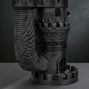 May include: A black, 3D-printed castle-shaped mug with a unique design. The mug features a tower with a crenelated top, arched windows, and a curved handle adorned with a wing motif. The mug is approximately 6 inches tall.