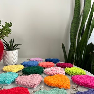 May include: A collection of colorful crocheted heart-shaped earrings. The earrings are made with a variety of colors, including red, orange, yellow, green, blue, purple, and pink.