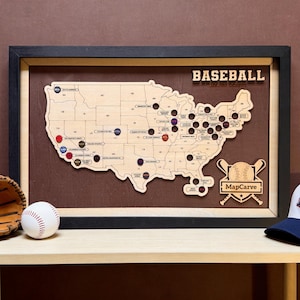 May include: A framed wooden map of the United States featuring baseball team locations with circular markers. The text BASEBALL and MapCarve are visible. A white baseball and a brown leather baseball glove are positioned in the foreground.