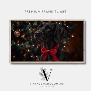 Puede incluir: Una impresión de arte digital enmarcada rectangular titulada PREMIUM FRAME TV ART que muestra un perro negro con una pajarita roja de lunares frente a un árbol de Navidad con luces. Debajo está el logo VINTAGE HEIRLOOM ART COLLECTIVE.