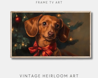 Op de afbeelding: Een schilderij van een bruine teckel met een rode strik voor een kerstboom met lichtjes. Het schilderij is ingelijst in een licht houten lijst.